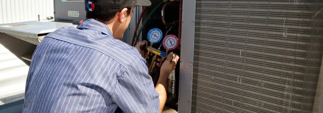 HVAC technician servicing a condenser unit in East Palo Alto